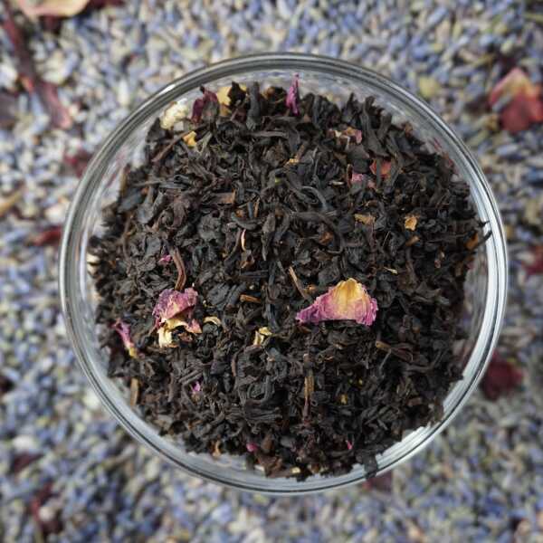 Schwarzteeblätter mit rosa-roten Rosenblütenblättern