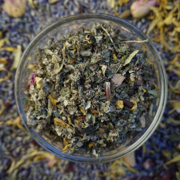 Kräuterteemischung mit grünen, orangefarbenen und rosa Bestandteilen